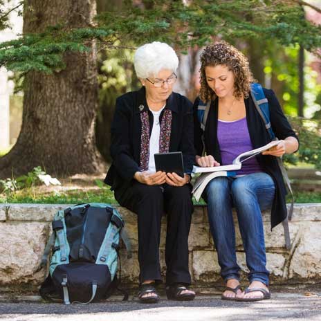 An older woman and a younger woman reading a book together